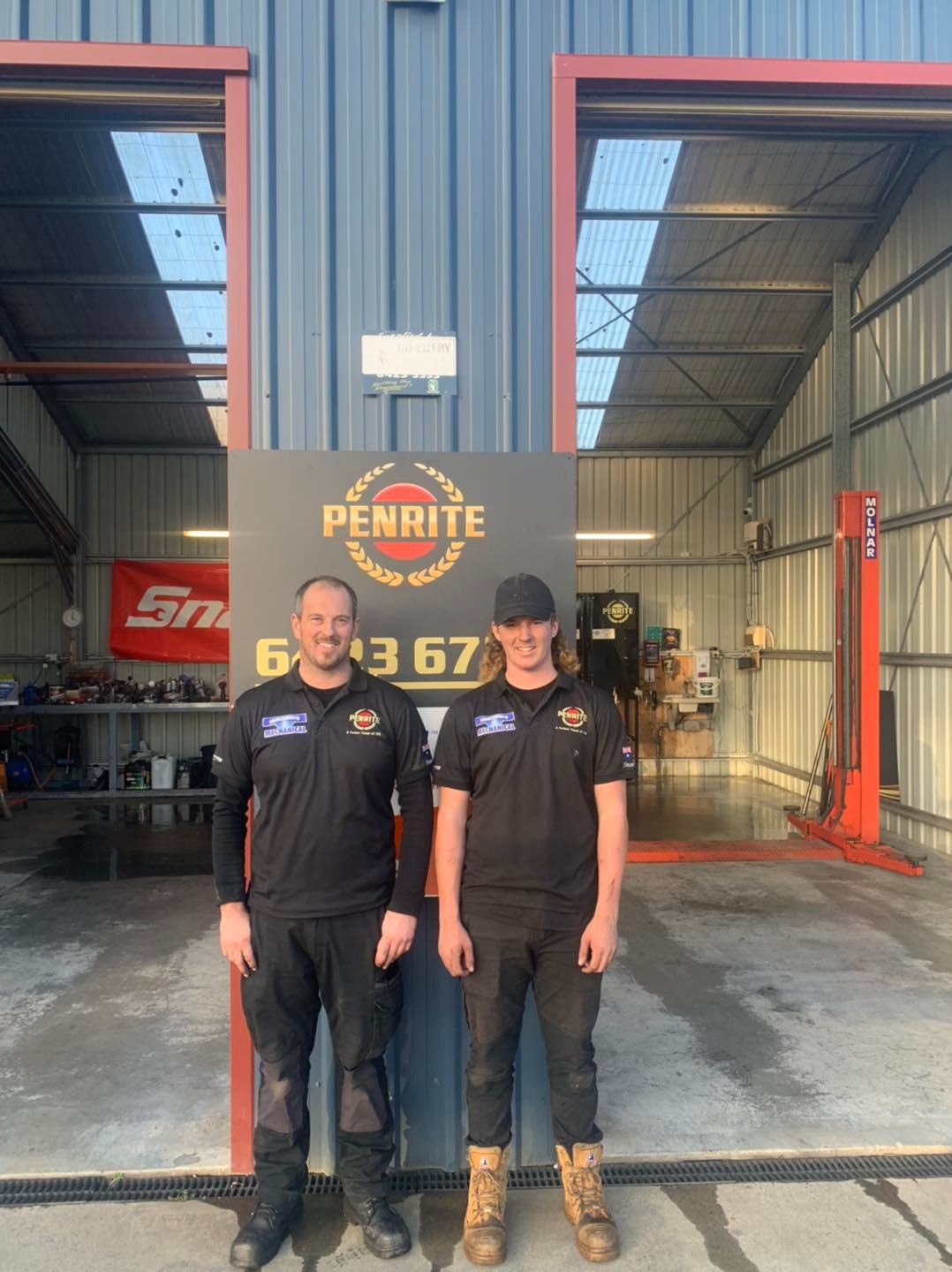 Two of the Charlesworth Mechanical team in branded shirts, standing in the workshop doorway