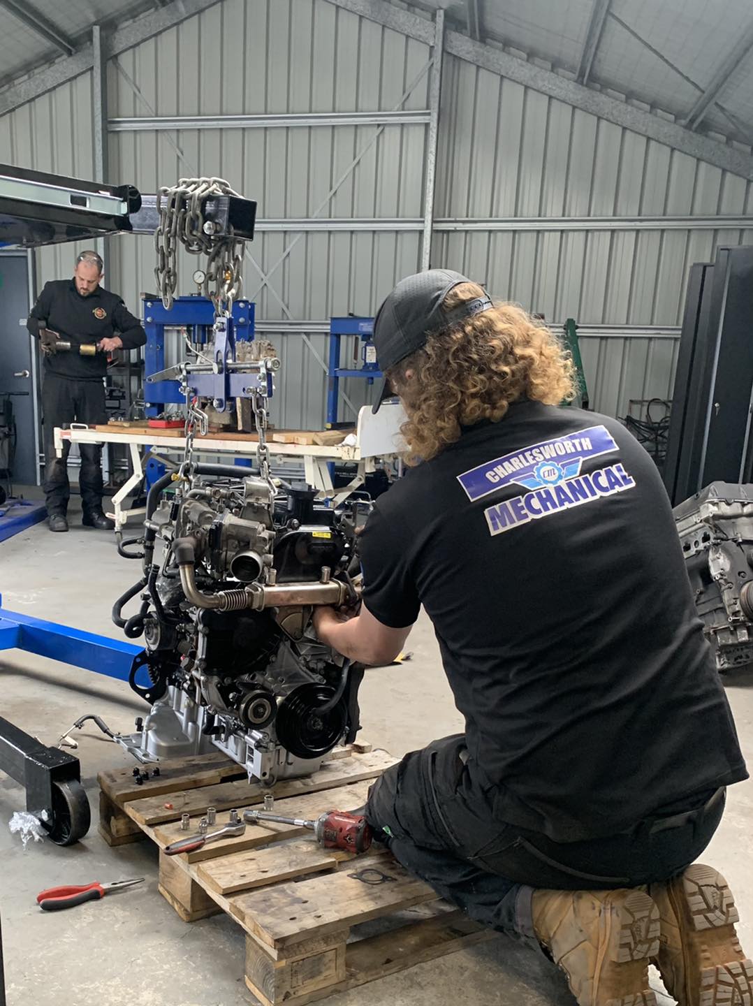 An engine out of the car on a pallet, being worked on in the Charlesworth Mechanical workshop
