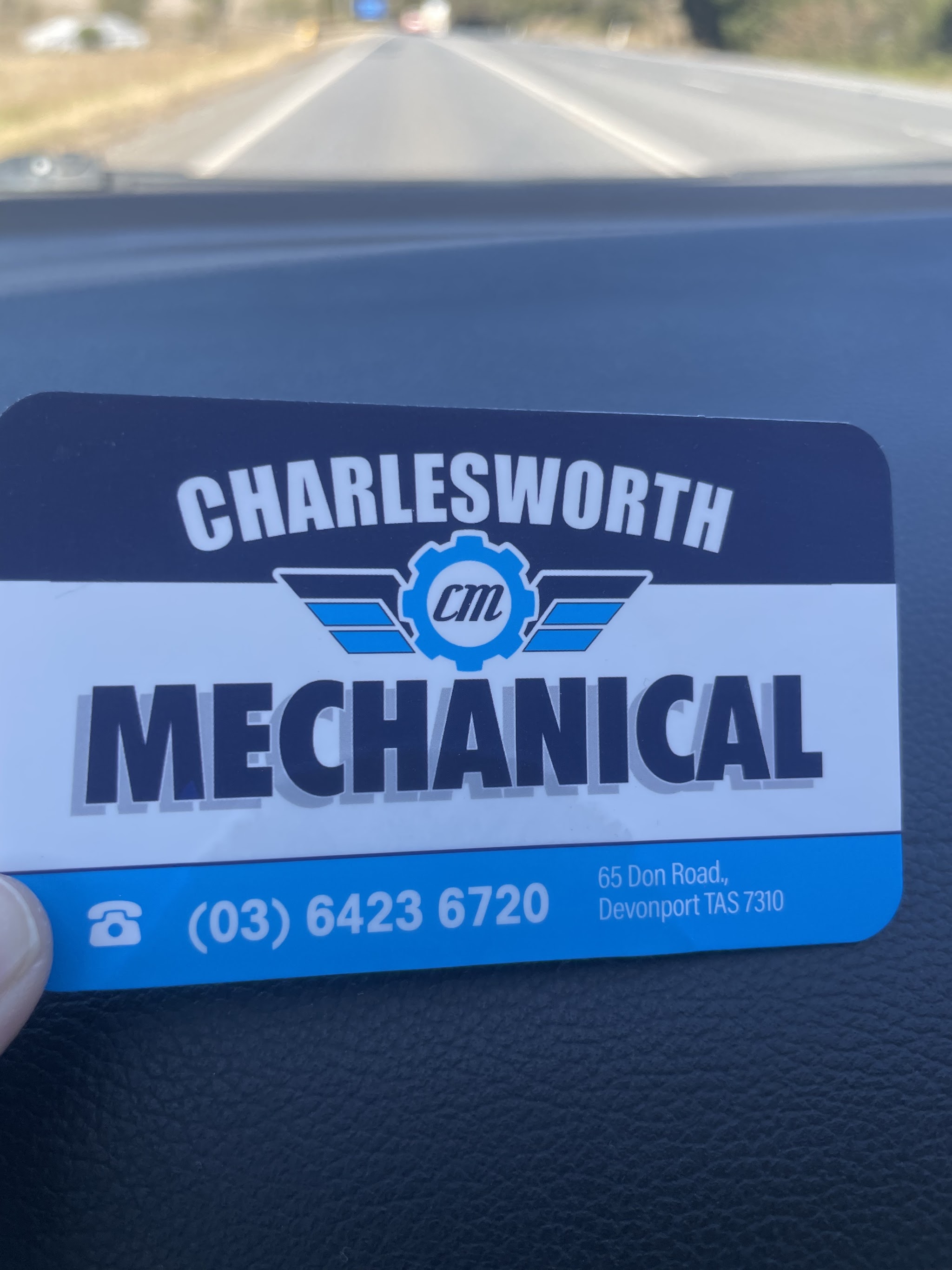 A Charlesworth Mechanical business card held up on a car dashboard